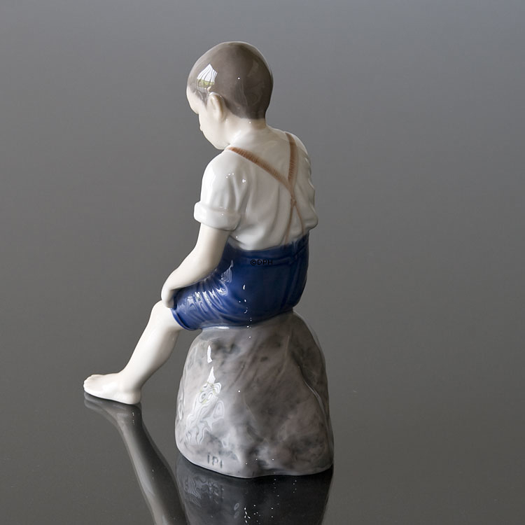Junge sitzt auf einem Stein und rollt seine Hose auf, Bing & Gröndahl Figur Nr. 1757
