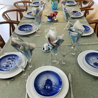 Festliche Tafel für eine Konfirmation oder einen Geburtstag mit Désirée Muttertagstellern, weißen Esstellern und Weingläsern. Inspiration für Festtafeln mit grüner Tischdecke und Blumen.