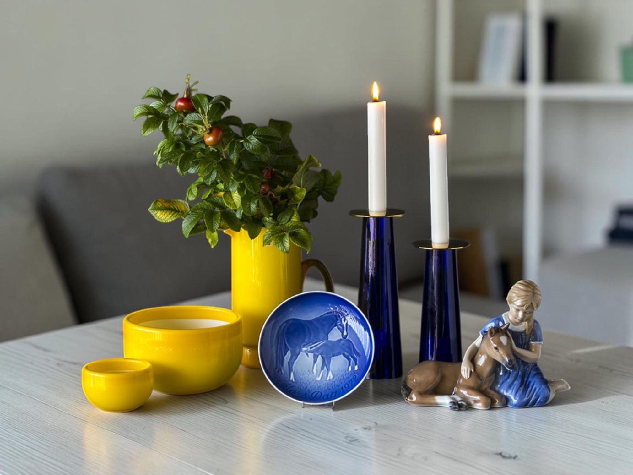 Bing & Gröndahl Muttertagsplatte mit Pferd verwendet in blau-gelber Tischdekoration mit Kerzenhaltern, Schüssel und Royal Copenhagen Figur