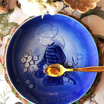 Désirée Muttertagsteller von 1974 mit einem Motiv eines Mädchens und Blumen, gedeckt für ein Sommerdessert mit goldenem Dessertbesteck.