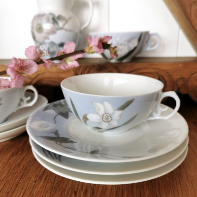Royal Copenhagen Jugendstil-Teeservice mit handgemalten Blumen, arrangiert mit Teetasse, Untertasse und Tellern in hellblauen und weißen Tönen.