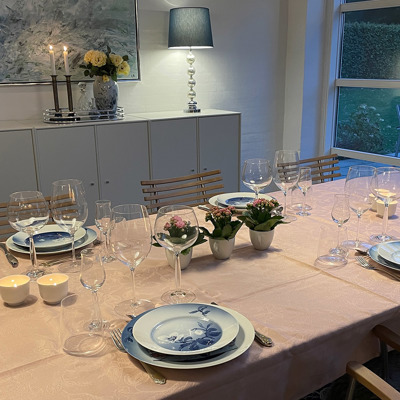Tisch gedeckt mit rosa Tischdecke, Bing & Gröndahl Weihnachtsrosen-Service und Vintage-Kaffeetassen, die als Blumentöpfe verwendet werden. Eine persönliche und charmante Tischdekoration für eine Feier oder ein gemütliches Abendessen.