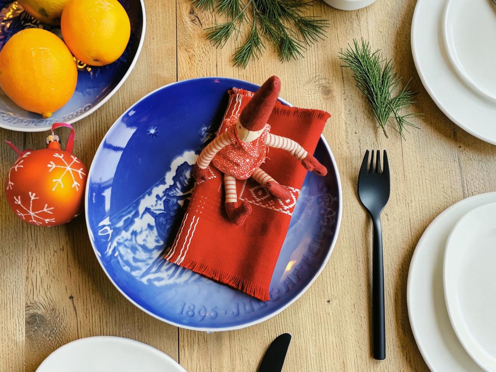 Bing & Gröndahl Weihnachtsjubiläumsteller gedeckt mit roter Serviette und Wichtel auf dem Weihnachtstisch mit Tannengrün und Weihnachtsschmuck