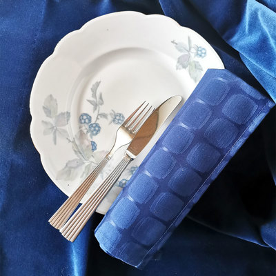 Altrohlau Porzellanteller mit Brombeer-Dekoration, gedeckt mit Besteck und blauer Serviette auf blauer Tischdecke. Klassische und schlichte Tischdekoration.