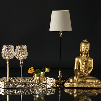 Buddha neben kleiner Lampe und Spiegeltablett mit Kerzenhaltern