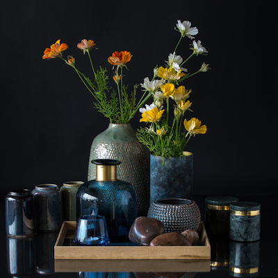 Große Vase mit blauer Flasche und kleinem Blumentopf auf Tablett mit Vasen und Marmorkruken drumherum