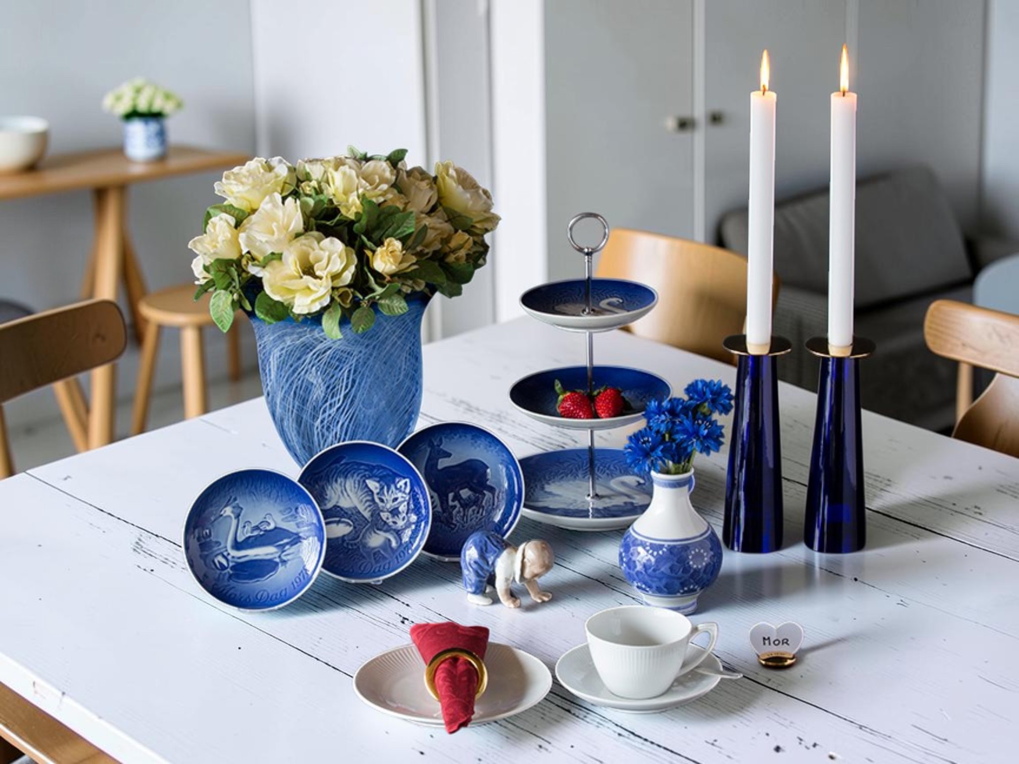 Bing & Gröndahl Muttertagsplatten verwendet als blau-weiße Teller in der Tischdekoration mit Blumen, Kerzen und Kuchenetagere
